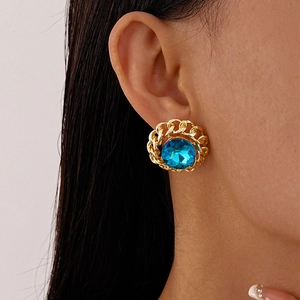 Detail of round sky blue gemstone earrings with golden chain border worn by a model
