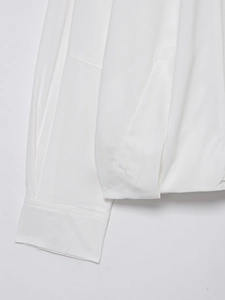 Detailed macro view of white linen bomber jacket showing fine stitching on pocket and cuff
