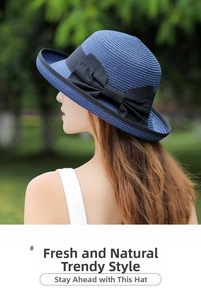 Detail of navy blue straw sun hat featuring a large black bow and fine woven texture