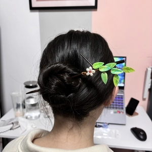 Bamboo style wooden hair pin with green leaf and flower worn by a model