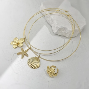 Set gioielli dorati con collane a stella marina conchiglia e anello a fiore su sassi