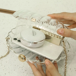 Elegante durchsichtige Acryl-Clutch in Muschelform mit goldener Kette von Model gehalten