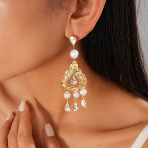Close-up of vintage gold drop earrings with pearls and crystals on a female model