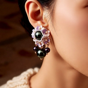 Close-up of vintage floral pearl drop earrings featuring green and purple pearls