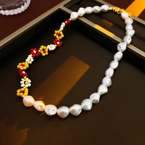 Detail of a gold plated pearl necklace with colorful beaded flowers in a jewelry box