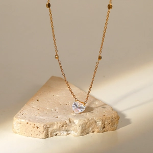 Detailed view of an 18K gold plated necklace with heart zircon and golden beads