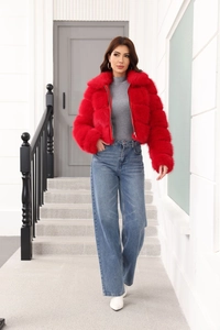 Short faux fur jacket in vibrant red paired with blue wide-leg jeans in outdoor setting
