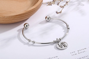 Detail of silver stainless steel open bracelet with LOVE and paw print charm pendant