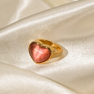 Bague cœur en or 18 carats avec pierre œil de chat rose sur fond de soie beige satiné