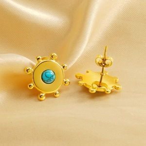Goldene Ohrstecker mit Sonnenmuster und Türkis auf champagnerfarbenem Satin