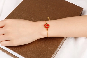 Close-up of a gold stainless steel adjustable bracelet with a red Love heart pendant