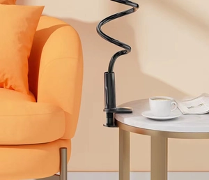 Adjustable black long arm tablet holder clamped to a marble table in a cozy home setting