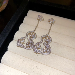 Macro shot of silver tassel earrings with hollow gourd shape and cubic zirconia inlay