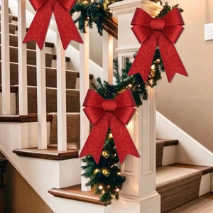 Red glitter Christmas bow ornament displayed on a decorated indoor wooden staircase