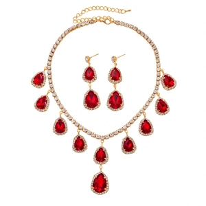 Parure de bijoux dorés avec pendentifs goutte rouges et détails en cristaux blancs