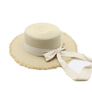 Detail of raffia boater hat with frayed edge and beige herringbone ribbon bow tie
