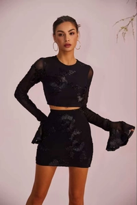 Détail d'un élégant ensemble noir deux pièces avec broderie florale et manches en résille