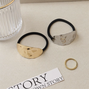 Minimalist elastic hair tie set with textured gold and silver metal charms on a white fabric