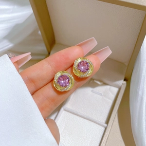 Close-up of pink zircon stud earrings with gold plating and sparkling small diamonds