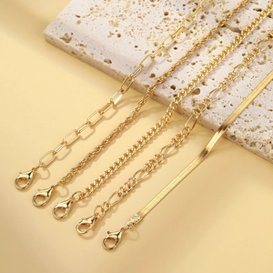 Close-up of four gold bohemian metal chains featuring paperclip and snake link designs
