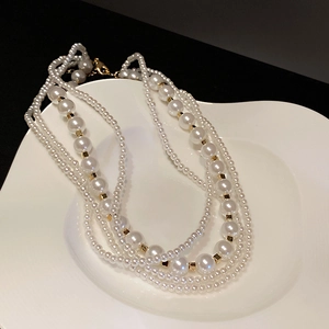 Detail of layered white pearls and gold hardware on an artistic display tray