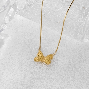 Golden butterfly pendant necklace with hammer texture and snake chain on foam
