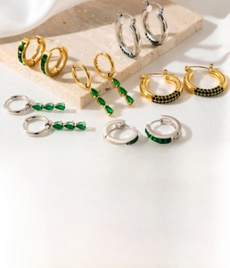 Detailed close-up of titanium steel teardrop earrings with green zircon in gold and silver