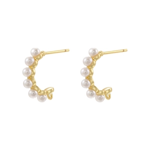 Detail shot of C-shaped gold earrings with six white pearls in a balanced layout
