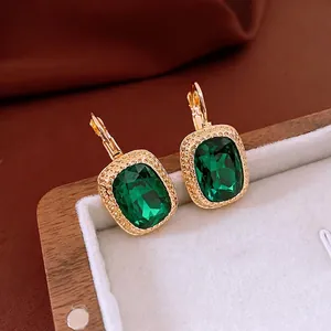 Vintage gold square earrings with emerald green crystals on white velvet lining