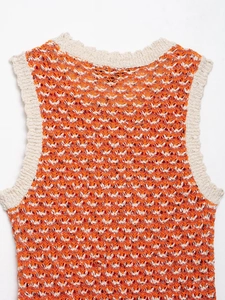 Close-up of bright orange textured knit fabric with creamy white ribbed neckline detail