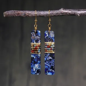 Detail of bohemian drop earrings with blue stone texture and gold wire wrapped beads