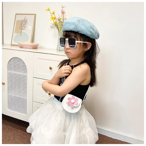 Detail of white cross-body bag with pink sequin flower and white sunglasses on a child