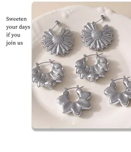 Macro shot of silver sunflower and wavy petal earrings on a white ceramic plate