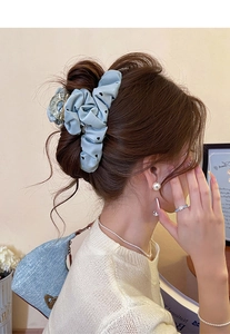Detail of light blue polka dot hair scrunchie with black hearts on a messy bun hairstyle