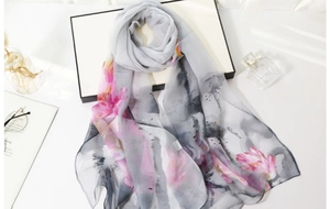 Detailed view of light gray silk scarf with elegant pink and orange ink flower prints