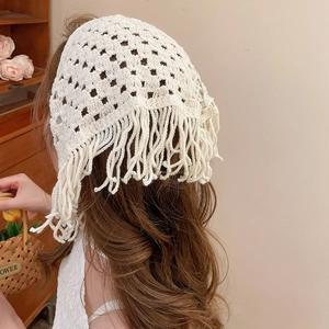 Close-up of white crochet triangular scarf featuring intricate knit textures and long fringes