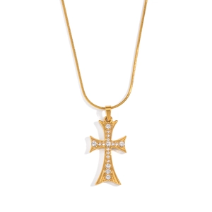 Détail d'un pendentif croix doré orné de zircons avec une chaîne serpent en métal brillant