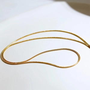 Close-up of a gold double-layer snake chain necklace with high-polish metallic texture