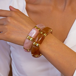 Detail of pink marble and amber acrylic resin bangles with gold metal spacers