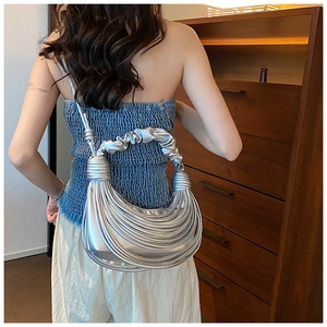 Detail of silver pleated crescent bag with knot shoulder strap on model back