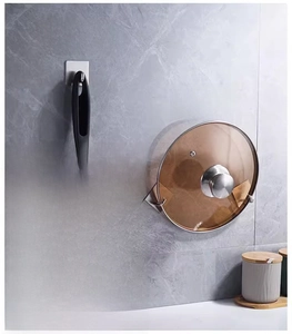 Strong stainless steel wall hooks holding a frying pan and pot lid on marble tile