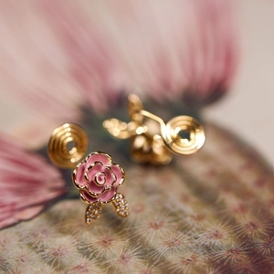 Macro shot of pink rose clip-on earrings with gold base and zircon-encrusted leaves