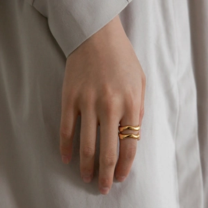 Detail shot of a golden minimalist wavy ring showcasing elegant curved metal lines