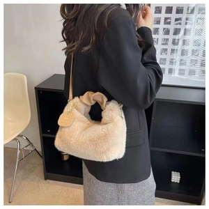 Detail of beige plush handbag with knotted handle design and golden chain decoration
