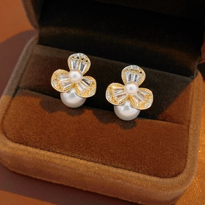 Detailansicht von Zirkon-Blumenohrringen mit großen weißen Perlen auf dunklem Samt