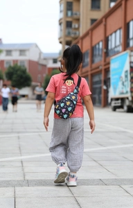 Outdoor shot of a black nylon kids chest bag featuring a colorful bird print on the back