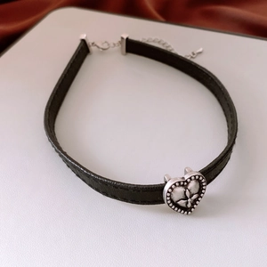 Detail of adjustable black leather choker with vintage silver embossed heart pendant