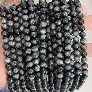 Macro shot of natural eagle eye stone beads with silky gray chatoyancy and smooth texture