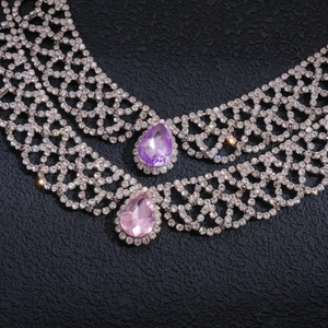 Detailed macro view of pear-cut purple and pink crystal drop necklaces with pavé rhinestones