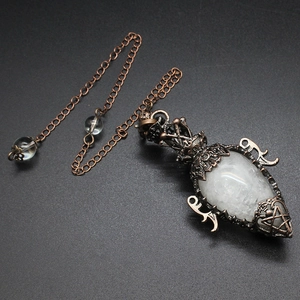Macro shot of clear crystal pendulum pendant with vintage bronze hollow metal frame and chain